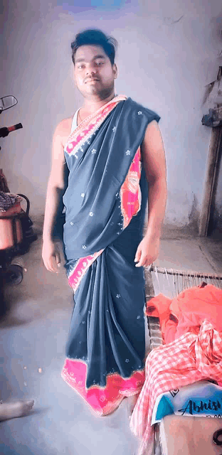 a man wearing a blue and pink saree stands in front of a motorcycle