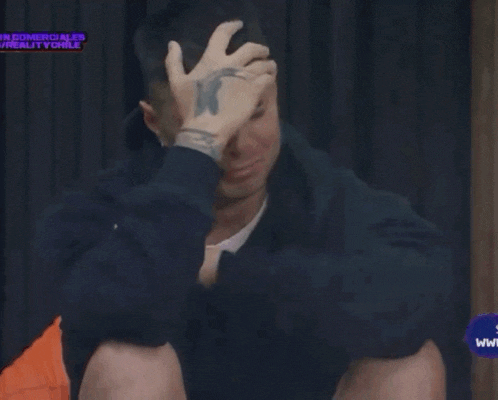 a man with a tattoo on his wrist holds his hand to his head