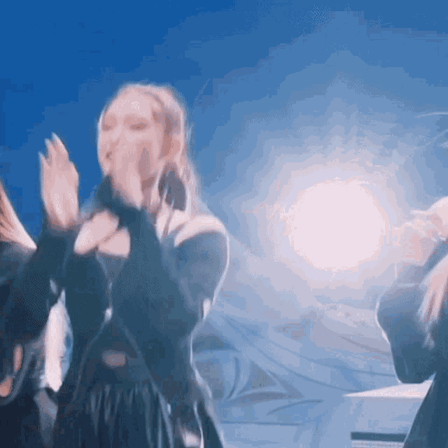a woman in a black dress is dancing in front of a blue sky .