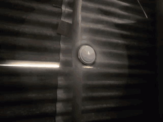 a white button is sitting on a metal wall