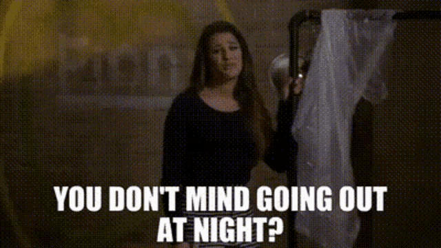a woman is standing in front of a sign that says you do n't mind going out at night .