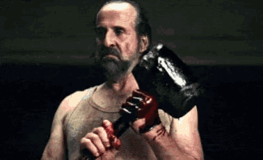 a man is holding a bloody hammer in his hands .