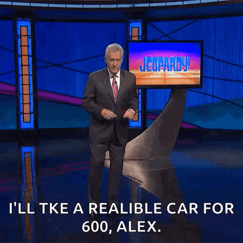 a man in a suit and tie stands in front of a television screen that says jeopardy