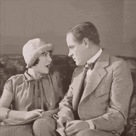a man and a woman are sitting on a couch and talking