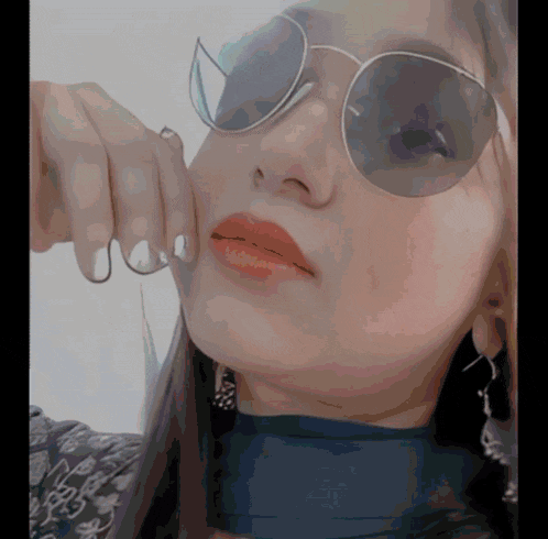 a close up of a woman wearing sunglasses and a blue top