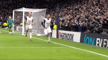 two soccer players are running towards a goal with a hankook ad in the background