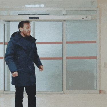 a man in a blue coat is walking through a hospital door