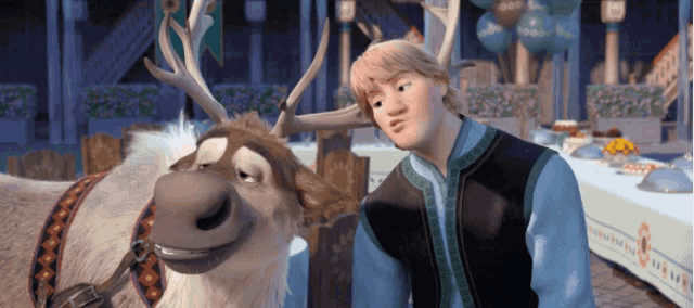 a man in a blue vest stands next to a deer