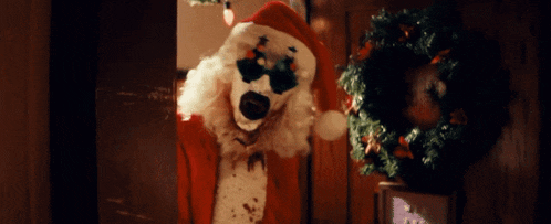a clown dressed as santa claus is standing in a doorway