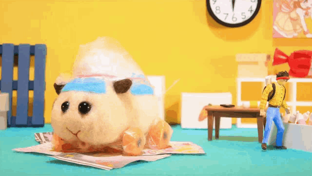 a stuffed animal is sitting on a magazine next to a man and a clock .