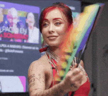a woman is holding a rainbow flag in front of a tv screen