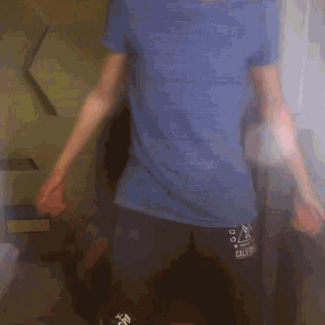 a man wearing a blue shirt and black shorts with the word californ on them