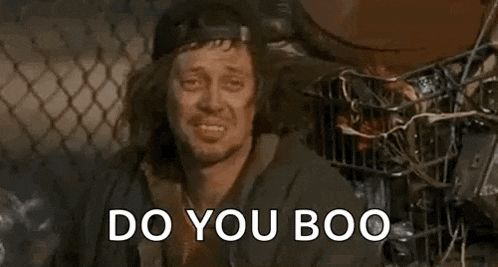 a man with long hair and a hat is sitting in a trash can .