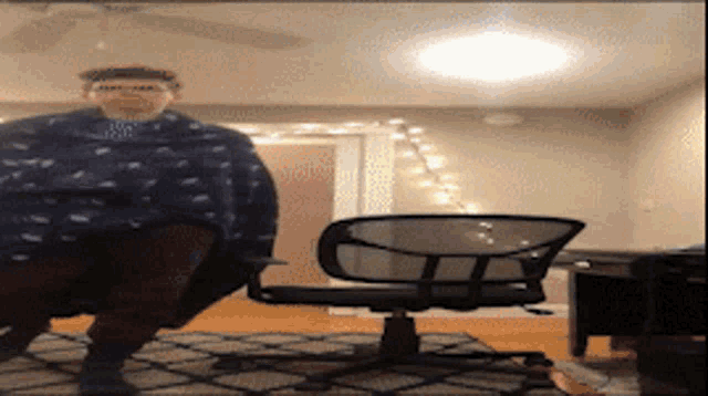 a man is sitting in a chair in a room with a ceiling fan