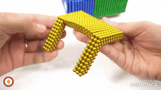 a person is holding a piece of gold magnetic balls
