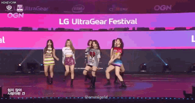 a group of girls are dancing in front of a large screen that says lg ultragear festival