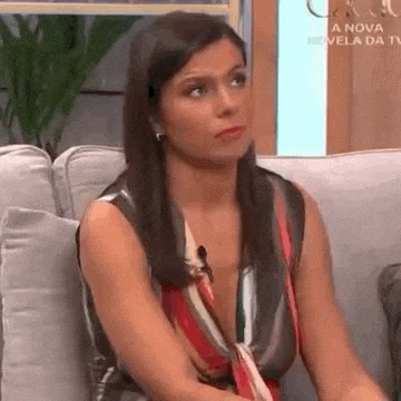 a woman is sitting on a couch with her arms crossed and making a funny face .