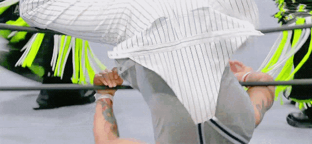a man in a striped shirt is doing a handstand in a boxing ring .