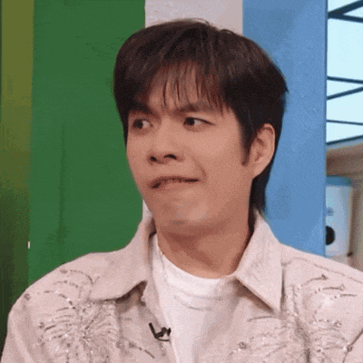 a young man is making a funny face while wearing a white shirt and a jacket .