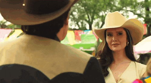 a woman in a cowboy hat is looking at a man in a cowboy hat .