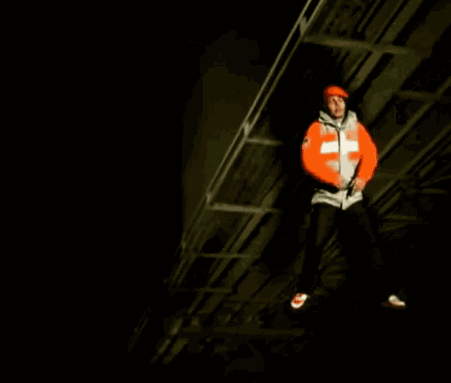 a man wearing a jacket with the letter t on it is jumping in the air