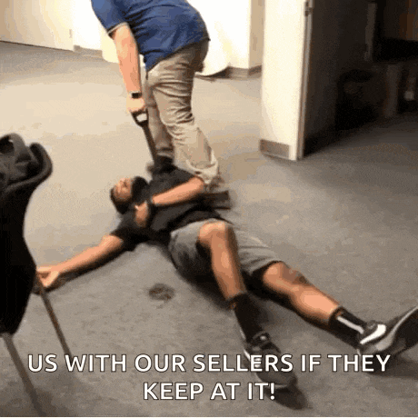 a man is laying on the floor with a cane in his hand while another man stands over him .