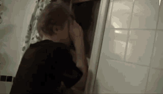 a man and a woman are kissing in a bathroom with a shower curtain .