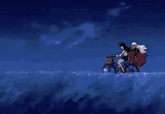 a man and a woman are riding a bike on a hill at night .
