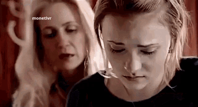 two women are standing next to each other with their eyes closed and one of them is crying .