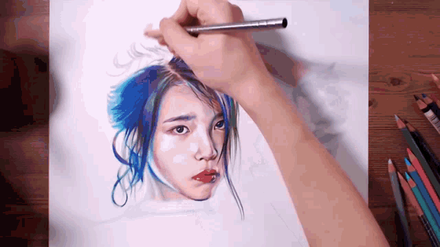 a person is drawing a girl 's face with colored pencils .