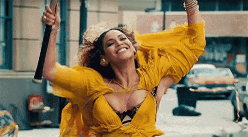 a woman in a yellow dress is holding a stick in the air .