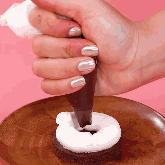 a person is frosting a cake with chocolate and marshmallows on a wooden plate