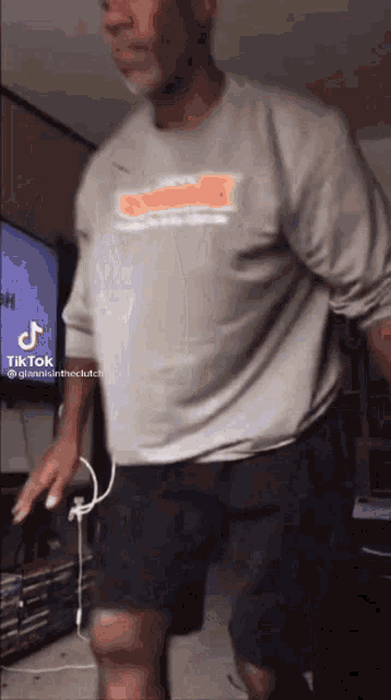 a man is dancing in front of a tv in a living room .