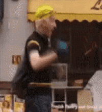a man wearing a yellow hat is standing in front of a store .