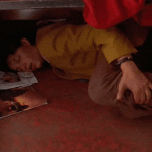 a woman in a yellow sweater is laying on the floor next to a magazine