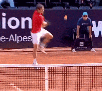 a man in a red shirt is swinging a tennis racquet on a tennis court in front of an advertisement for lavorol