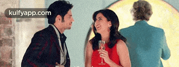 a man and a woman are sitting at a table holding wine glasses and looking at each other .