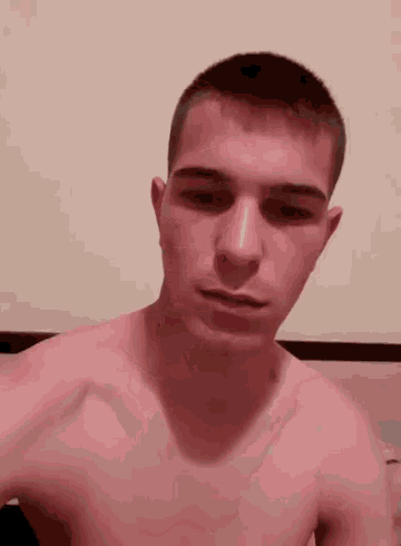 a young man without a shirt is sitting on a bed .