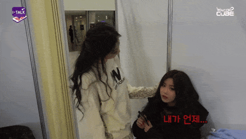 a girl wearing a white sweater with the letter n on it talks to another girl
