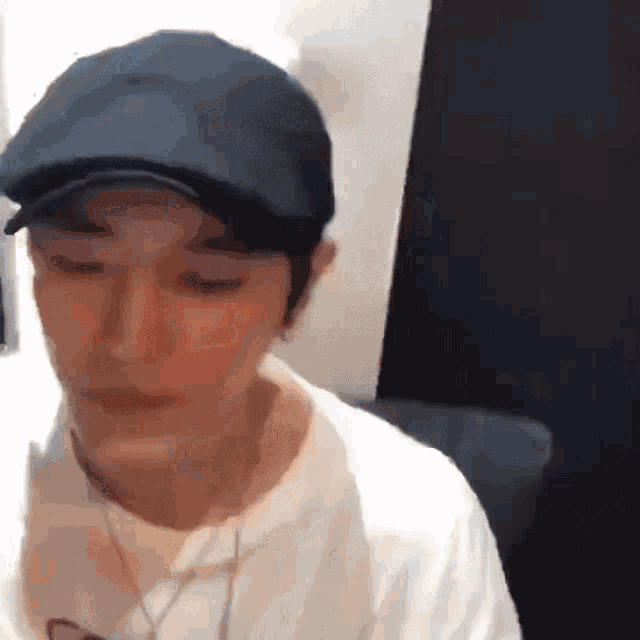 a man wearing a baseball cap and a white shirt is sitting in a room .