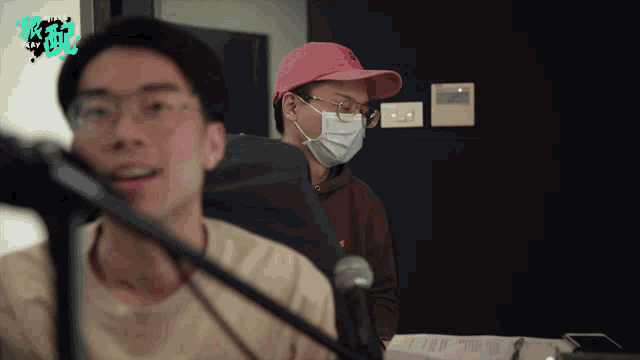 a man wearing a pink hat and a face mask stands next to another man