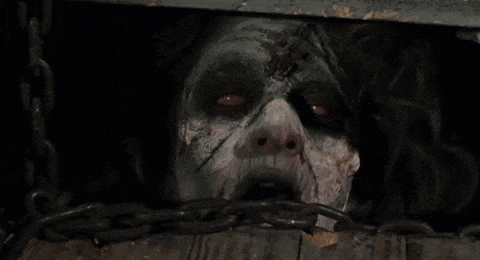 a close up of a zombie 's face coming out of a hole in a wooden box .