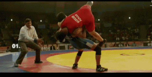 a wrestler wearing a red shirt that says ' success ' on it is being lifted by another wrestler