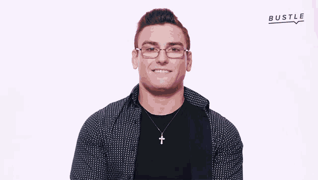 a man wearing glasses and a cross necklace with bustle written on the bottom right