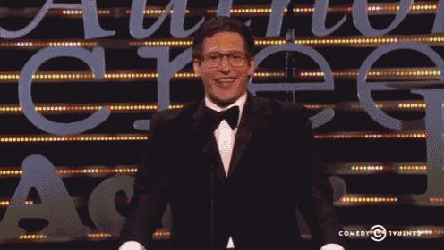 a man in a tuxedo and bow tie stands in front of a sign that says comedy central