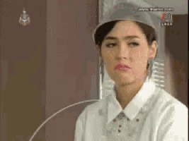 a woman wearing a hat and a white shirt is sitting in front of a television .