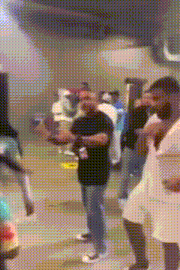 a group of people are standing in a room and one of them is holding a bottle of beer