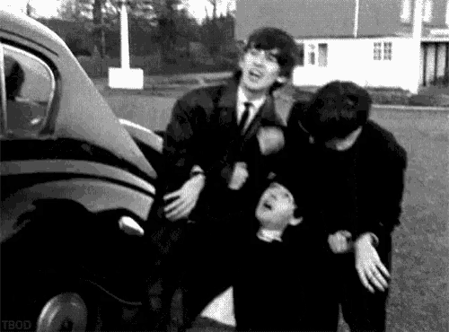 a group of young men are standing next to each other in front of a car in a black and white photo .