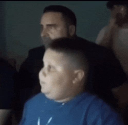 a blurry picture of a man giving a boy a haircut while wearing a blue shirt that says miami bulls