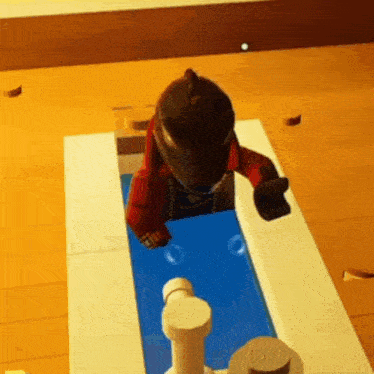 a lego figure is standing on top of a pool .